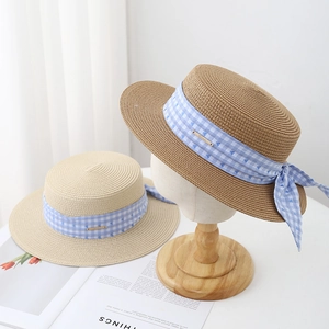 Classic boater hats with blue plaid ribbon and heart pattern in a cozy indoor setting