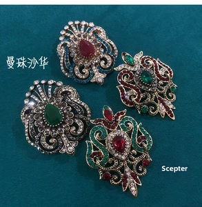 Macro detail of four vintage gold brooches with colorful rhinestones on teal fabric