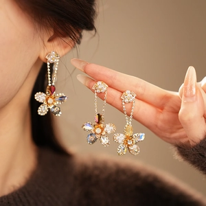 Detailed close-up of long floral drop earrings with white pearls and colorful crystals