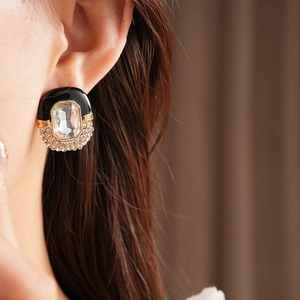 Close-up of a vintage oval stud earring with black enamel and octagonal crystal