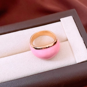 Primo piano di un anello bombato in smalto rosa e oro in una scatola marrone