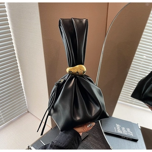 Close-up of black pleated cloud bag with elegant gold ring handle and leather tassel