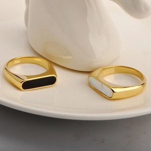 Detailed view of geometric gold rings featuring black agate and white shell inlays