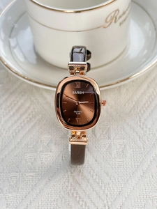 Detail of elegant rose gold oval watch with brown leather strap and roman numeral dial