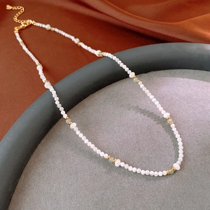 Detailed shot of beaded necklace with white shell pearls, green agate and gold accents
