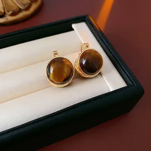 Boucles d'oreilles créoles dorées avec œil de tigre dans un écrin de luxe