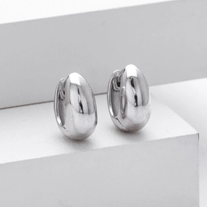 Close-up of a pair of polished silver oval hoop earrings on a clean white display stand
