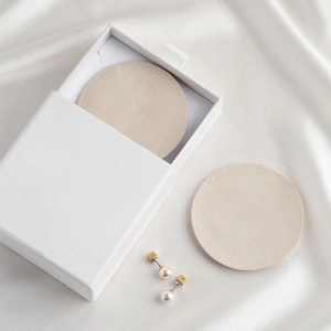 Detailed top view of a white jewelry drawer box with beige pads and pearl earrings on silk