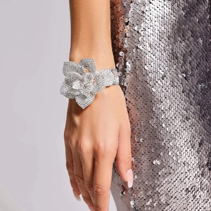Dettaglio di un grande bracciale a fiore argento con strass scintillanti sul polso
