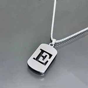 Gros plan détaillé d'un collier en acier inoxydable argenté avec pendentif lettre E évidé