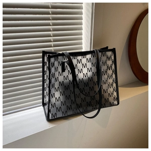 Detailed macro view of the large transparent tote bag with black letter M patterns