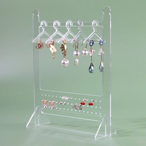 Macro view of clear acrylic earring organizer with mini clothes hangers for jewelry display