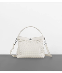 Close-up of cream woven leather texture and elegant metallic buckle on the handbag