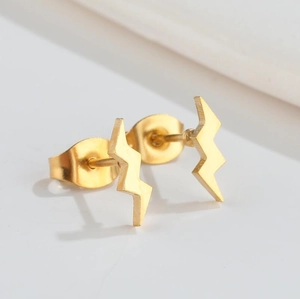 Macro shot of minimalist lightning bolt stud earrings in polished gold stainless steel
