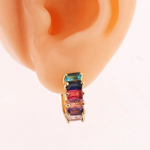 Close-up of golden hoop earrings with colorful cubic zirconia on a model ear