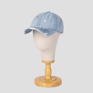 Detail of distressed light blue denim baseball cap with embroidery and frayed holes