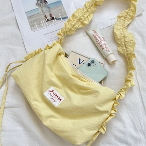 Detail of yellow nylon bag with ruffled strap and a woven SUZAKKA logo label
