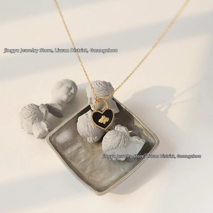 Macro shot of gold heart lock necklace with bee emblem and black inlay detail