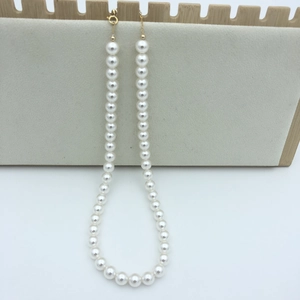 Detailed macro view of round white pearl necklace with adjustable gold clasp