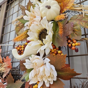 Nahaufnahme eines herbstlichen Hängers mit weißen Kürbissen, Sonnenblumen und Ahorn