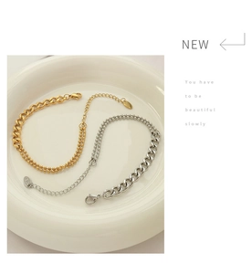 Detail of gold and silver layered cuban and bead bracelets on a white ceramic tray
