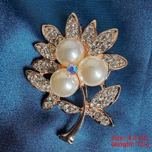Macro view of camellia brooch with pale yellow pearls and rhinestones on blue fabric
