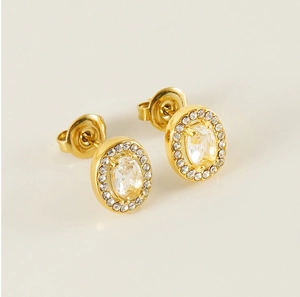 Macro detail of gold oval stud earrings with clear central stone and halo setting
