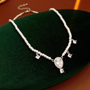 Detailed close-up of beaded pearl necklace with rhombus teardrop pendant on velvet