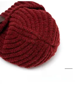 Detailed view of durable knitted top stitching on a wine red wool beanie hat