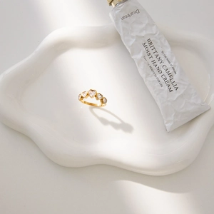 Elegante anillo de acero de titanio dorado con cinco circonitas de corazón en bandeja