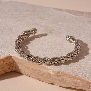 Macro shot of silver twisted metal cuff bracelet on natural stone with industrial texture