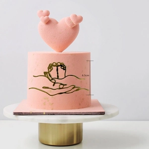 Detail view of 6.5cm gold baby shower cake topper with parent and child hand-foot line art