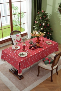 Detail of red Christmas tablecloth with reindeer patterns and beige tassel fringe edges