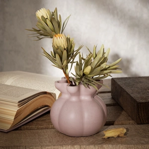 Detailed view of matte rose pink pleated ceramic vase with elegant ruffled edge and dried flowers