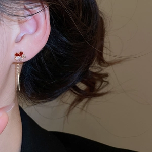 Close-up of four-leaf clover earring with red enamel and crystals on a female model