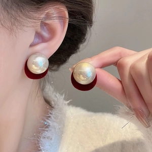 Close-up of elegant large white pearl earrings with luxury red velvet base detail