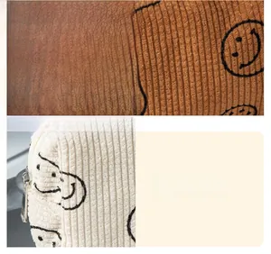 Macro view of corduroy fabric texture and smiley face print on large cosmetic bag