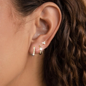 Close-up of golden S925 silver earring set with crystals worn on a female model