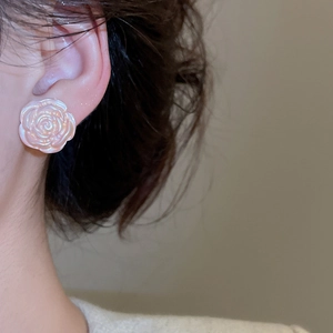 Close-up of elegant rose flower stud earrings with iridescent pearl texture on model
