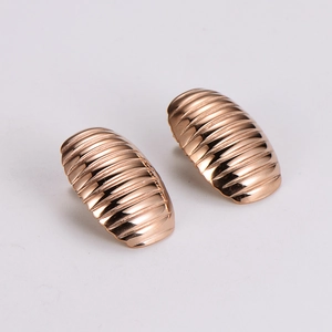 Macro detail of rose gold stainless steel earrings with textured vertical striped pattern