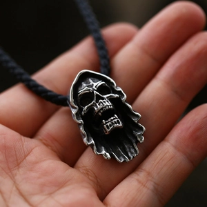 Detailed close-up of a silver gothic reaper skull pendant with a black woven cord