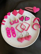 Close-up of pink micro-pave hoop earrings and heart hair clip on a spotted white tray