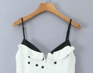 Détail d'une robe blanche à pois avec fines bretelles et col en V à revers unique
