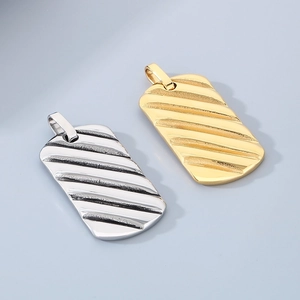 Close-up of gold and silver rectangular dog tag pendants with textured wave pattern