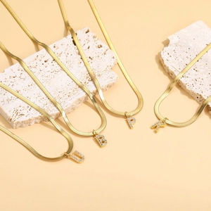 Detail of gold snake chain necklaces with zircon-studded letters U B P and K on stones