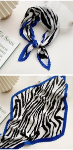 Detailed view of pleated zebra print silk scarf with vibrant blue edge trim detailing