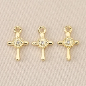 Baroque 18K gold-plated cross pendants with clear gems set on a minimalist beige fabric
