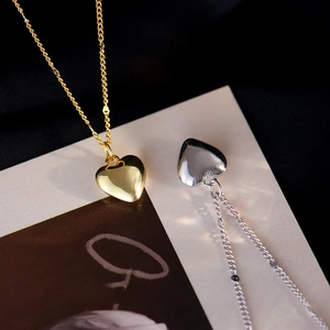 Elegant heart pendant necklace set in gold and silver finish on a luxury dark fabric