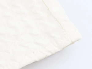 Vue macro de la texture matelassée blanche et des coutures fines sur la robe élégante