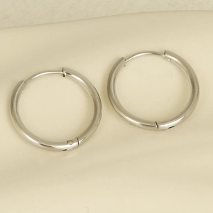 Detailed close-up of pair of polished 304 stainless steel silver hoop earrings on fabric